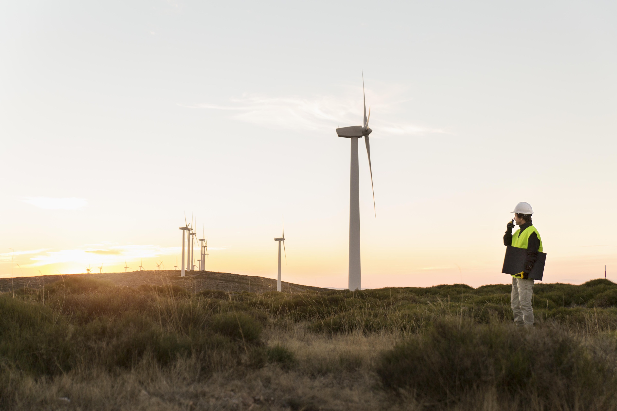 Wind turbines across fields with an engineer observing the site