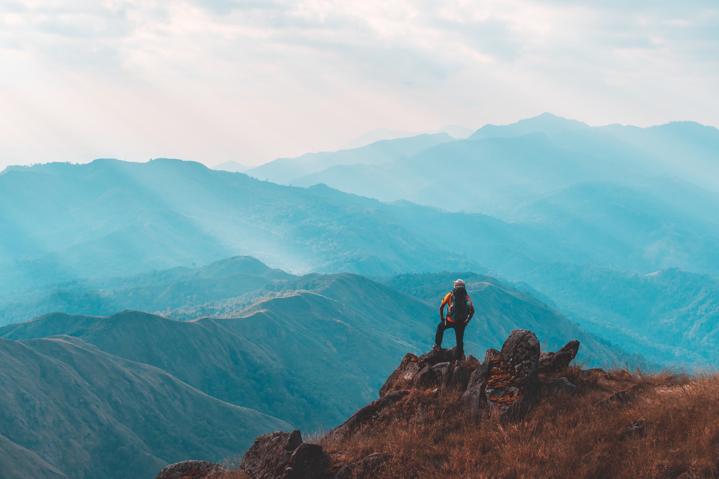 Hiker standing on a mountain summit overlooking distant peaks